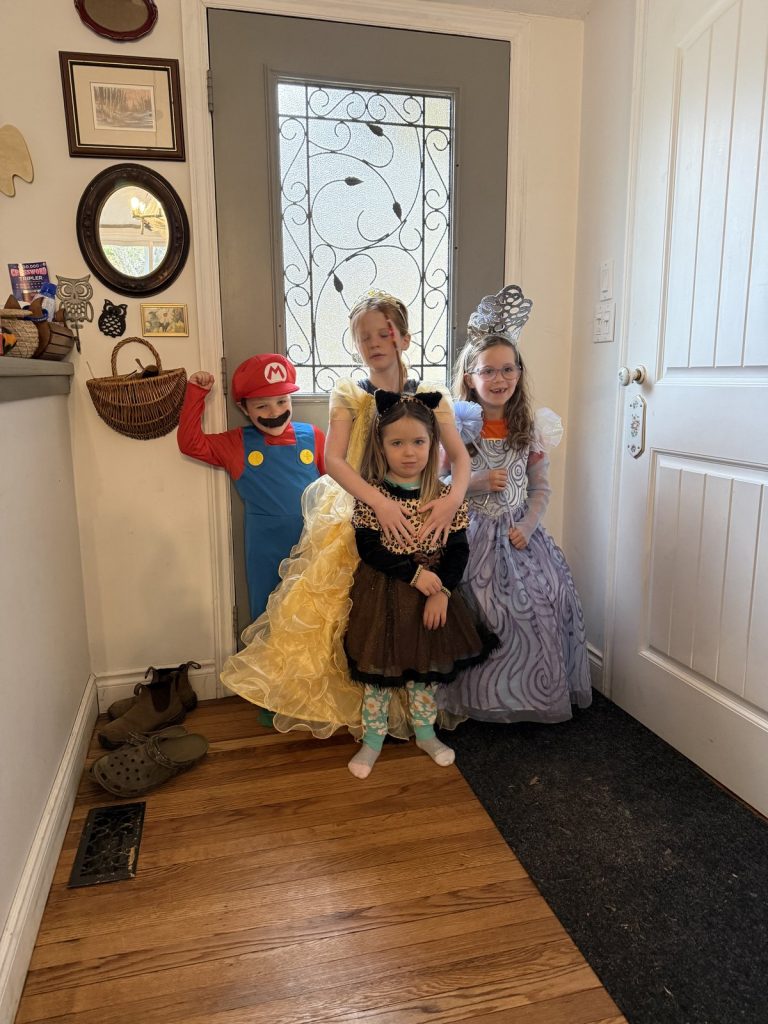 Four children in Halloween costumes at the front door, ready to head out